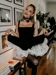 A woman in a black and white dress is sitting on a chair in a room with books and decor.