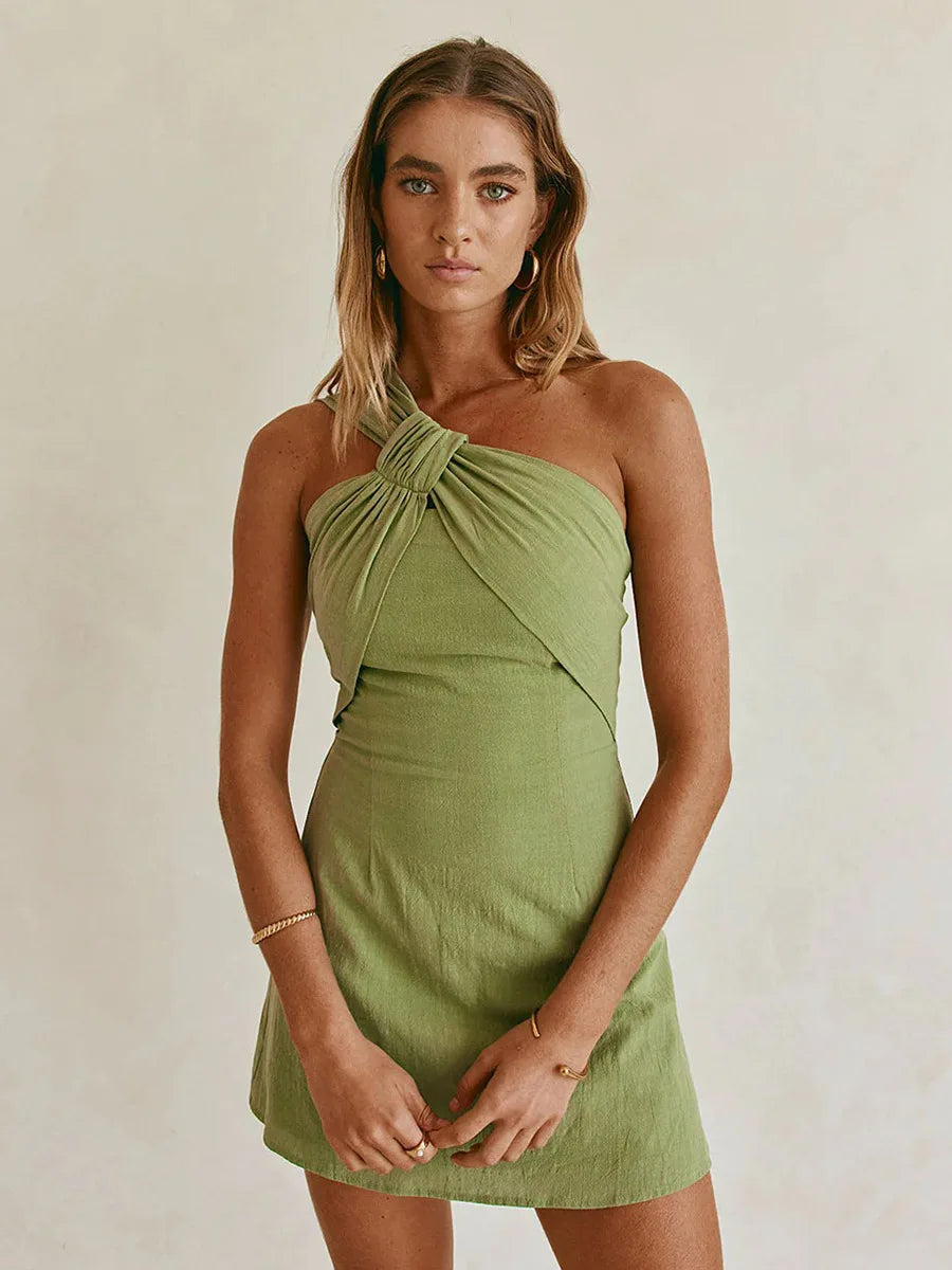 Woman wearing a green halter neck dress against a plain background