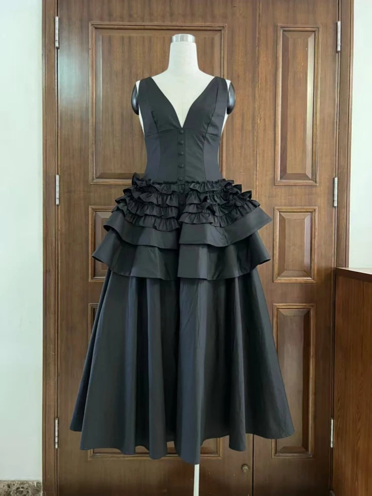 Black dress with ruffled layers on a mannequin against a wooden door background
