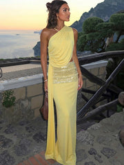 Woman in a yellow evening gown with a sequined skirt standing on a scenic balcony.