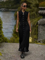 Woman in a black dress walking outdoors with greenery in the background