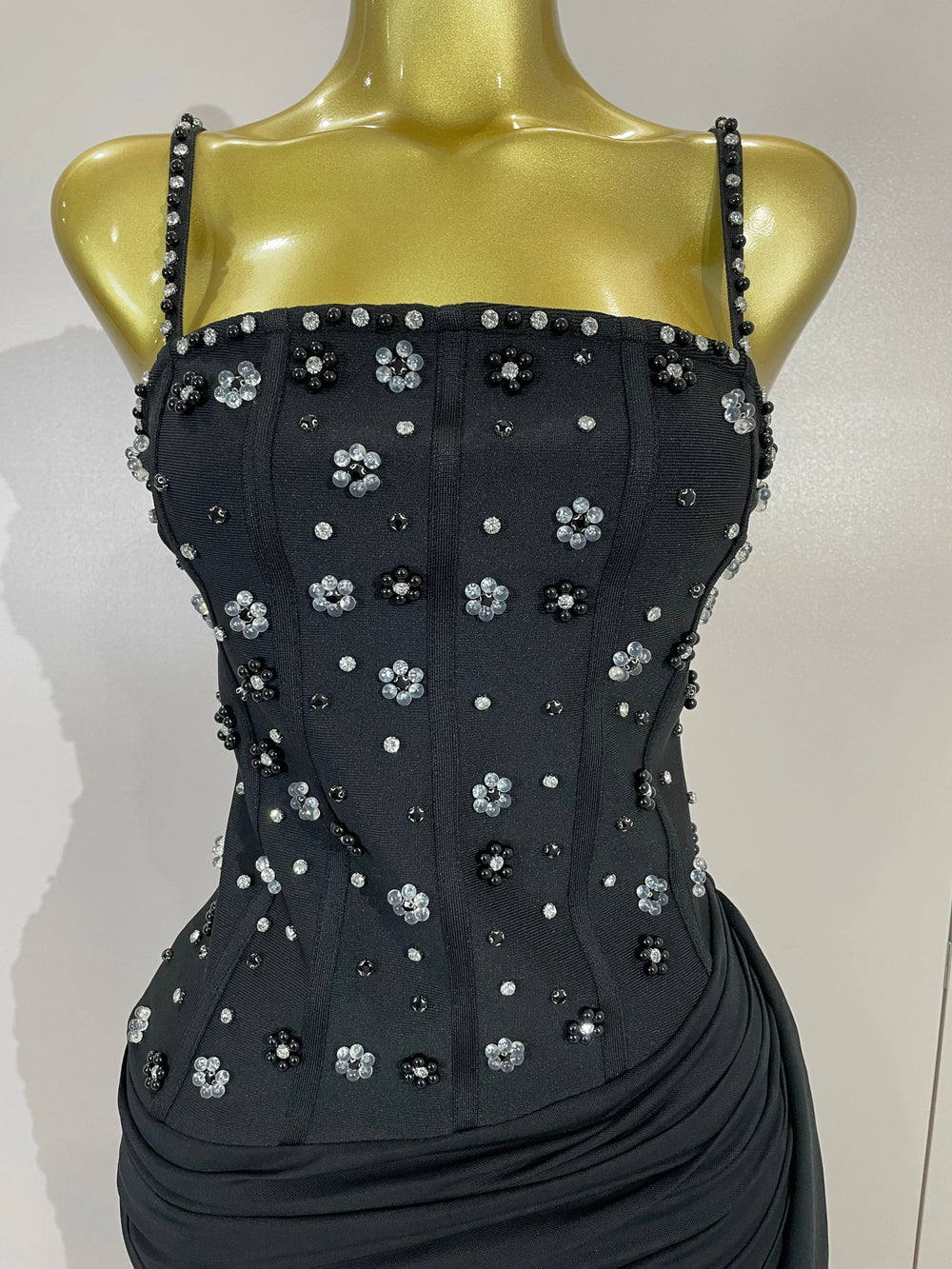Side profile of a black embellished bodycon dress on a mannequin