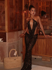 Woman in a black sequin dress standing in a spa-like setting with a woven bag.