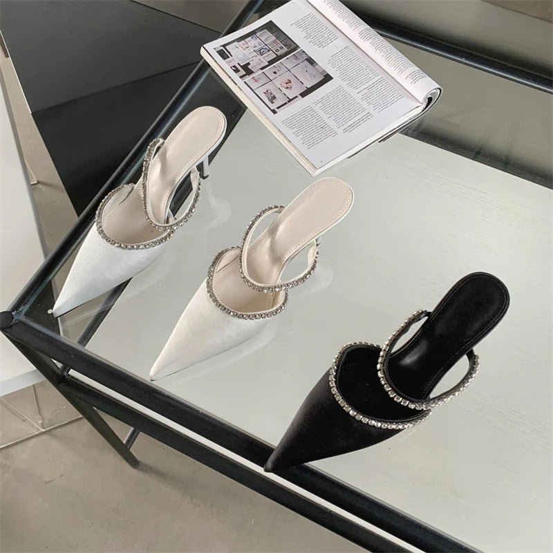 Two pairs of heeled shoes on a glass table with a magazine underneath.