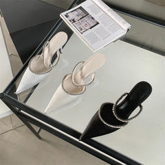 Two pairs of heeled shoes on a glass table with a magazine underneath.