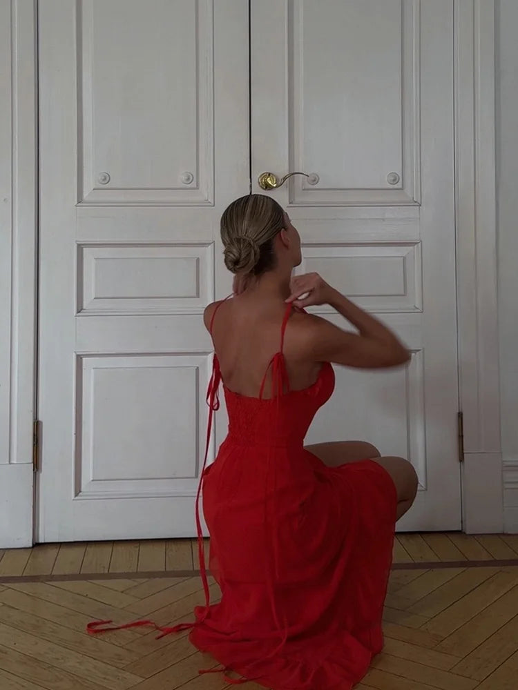 Woman in a red dress sitting on the floor in front of a white door.