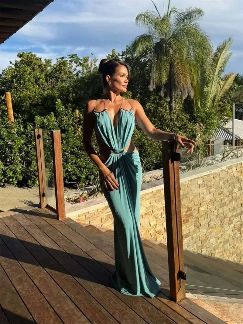 Teal halter neck draped maxi dress with gold chain detail on a wooden deck