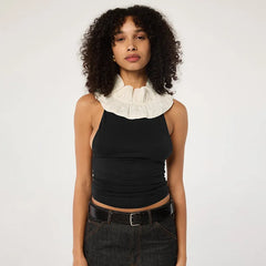Woman wearing a black sleeveless top with a white ruffled collar against a plain background