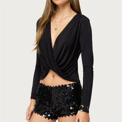 Black long-sleeve top with a draped design and black sequin shorts on a white background
