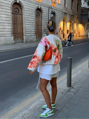 Person walking in a floral quilted bomber jacket on a street