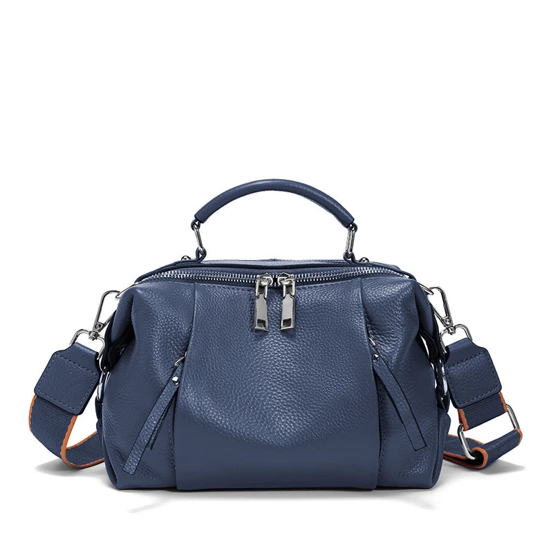 Blue handbag with multiple zippers on a white background