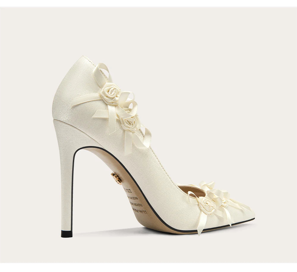 White high-heeled shoe with floral details on a light gray background