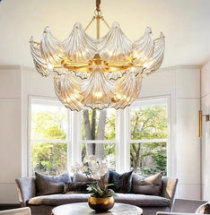 Luxurious chandelier hanging above a living room with a gray sofa and large windows.