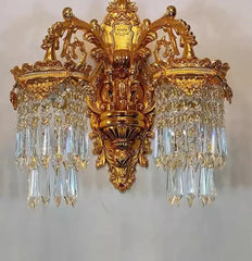 Ornate gold wall sconce with crystal accents on a plain background