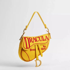 Yellow saddle bag with red 'Dracula' print and 'D' hardware