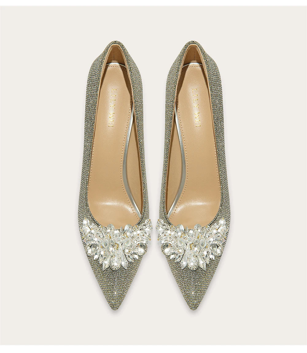 Pair of glittery high-heeled shoes with crystal embellishments on a light gray background
