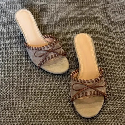 Khaki open toe square heel mules with stitched trim and bow detail, top down view