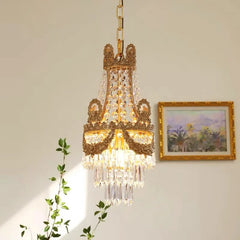 Decorative chandelier hanging in a room with a painting and plant.