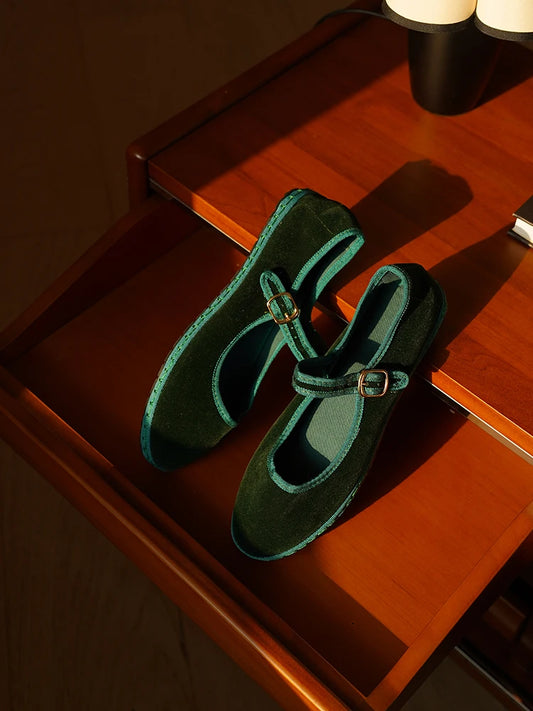 Dark green velvet Mary Jane flats with a contrasting teal trim and gold buckle.
