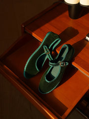 Dark green velvet Mary Jane flats with a contrasting teal trim and gold buckle.