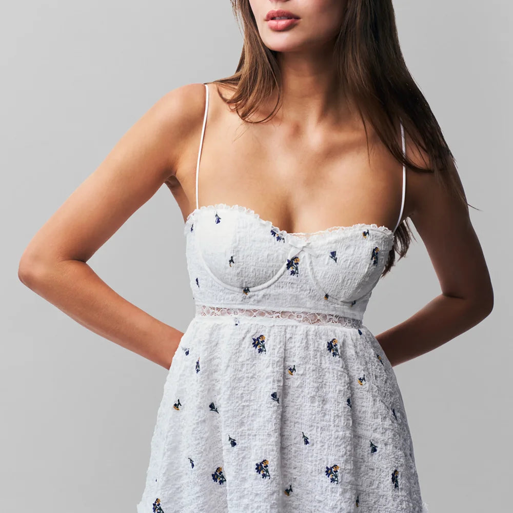 Woman wearing a white floral dress against a gray background