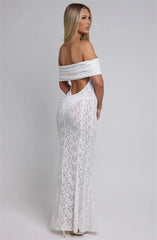 Woman wearing a white lace off-shoulder dress on a plain background