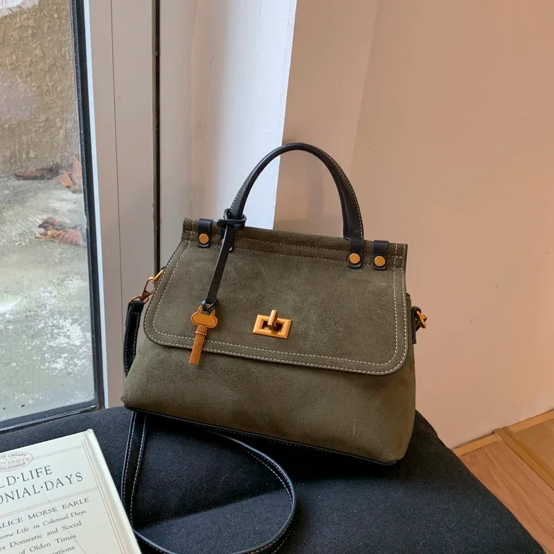 Green handbag on a chair next to a book