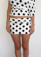 Person wearing a polka dot top and skirt set against a white background