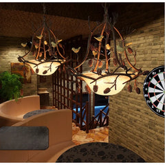 Decorative chandelier with branches and leaves in a room with a dartboard.