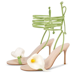 Green strappy high-heeled sandals with a white flower on a white background