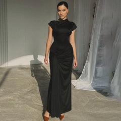  Golden Atelier maxi dress with short sleeves and a tie-up detail at the waist. The dress hugs the curves and is modeled on a woman in a summery setting. Black