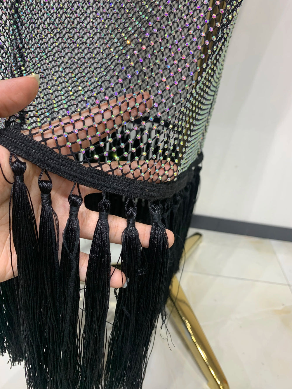 Close-up of a black beaded clutch with tassels held by a hand.