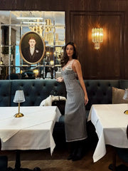 Woman in a patterned dress standing in a stylish restaurant with elegant decor.