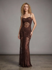 Woman wearing a brown evening gown with lace detailing against a gray background