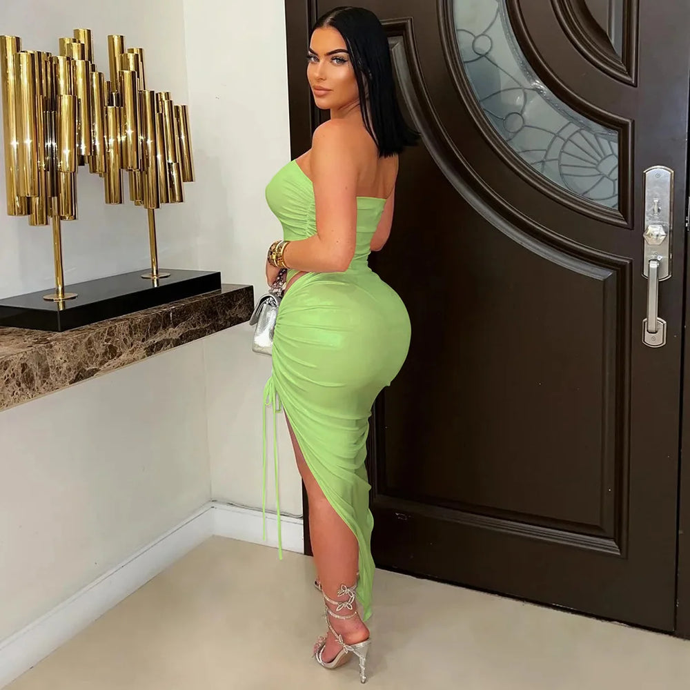 Woman in a green dress standing in front of a dark door.