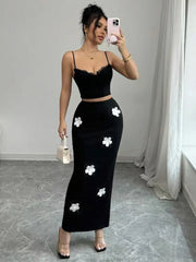 Woman taking a mirror selfie wearing a black outfit with white floral patterns in a room.