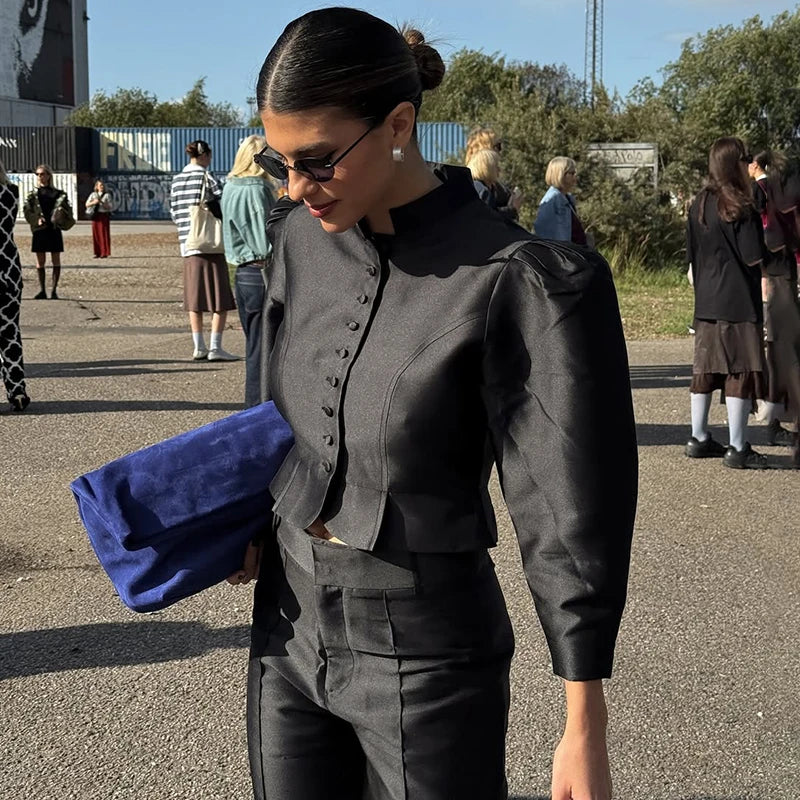 Woman in a black outfit holding a blue clutch with people in the background