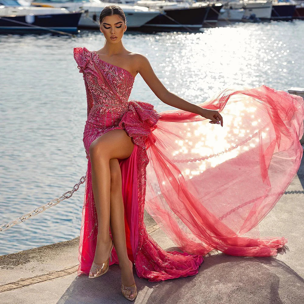 Woman in a pink dress by a waterfront with boats in the background