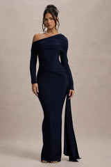 Woman wearing a navy blue one-shoulder gown against a beige background