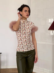 Woman wearing a floral top with fluffy sleeves in a room with white tiled walls.