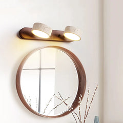 Round mirror with wooden frame and two wall-mounted lights on a light-colored wall.