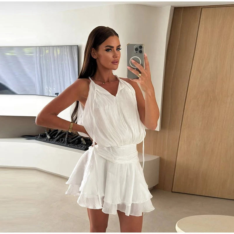 Woman taking a mirror selfie wearing a white dress in a modern room.