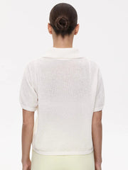 Person wearing a white short-sleeve cardigan on a plain background