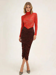 Woman wearing a red sheer top and brown ruched skirt on a white background