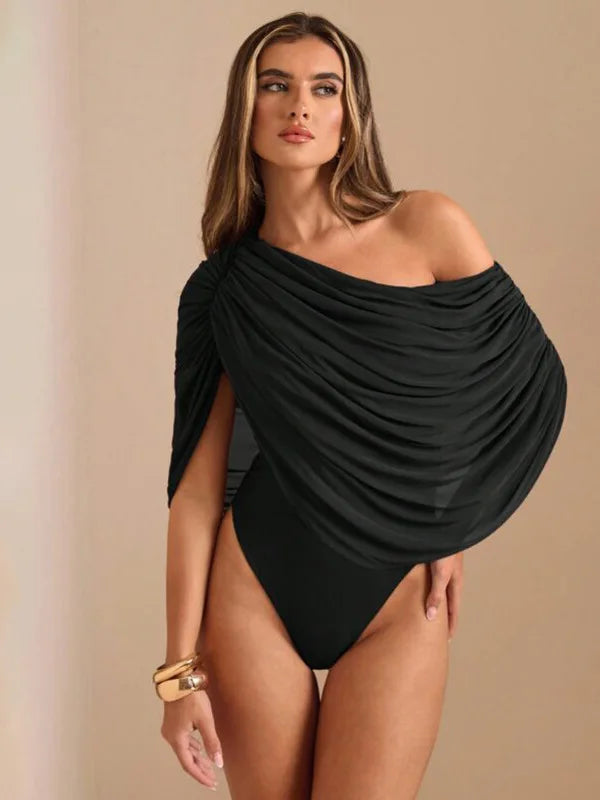 Woman wearing a black off-shoulder swimsuit against a beige background