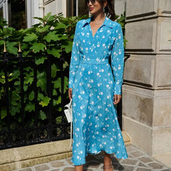 Woman wearing a blue floral dress standing in front of a building.
