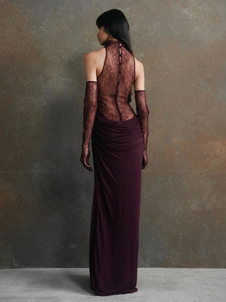 Woman wearing a dark burgundy evening gown with sheer lace detailing against a gray background