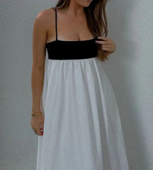 Woman wearing a black top and white skirt against a gray wall