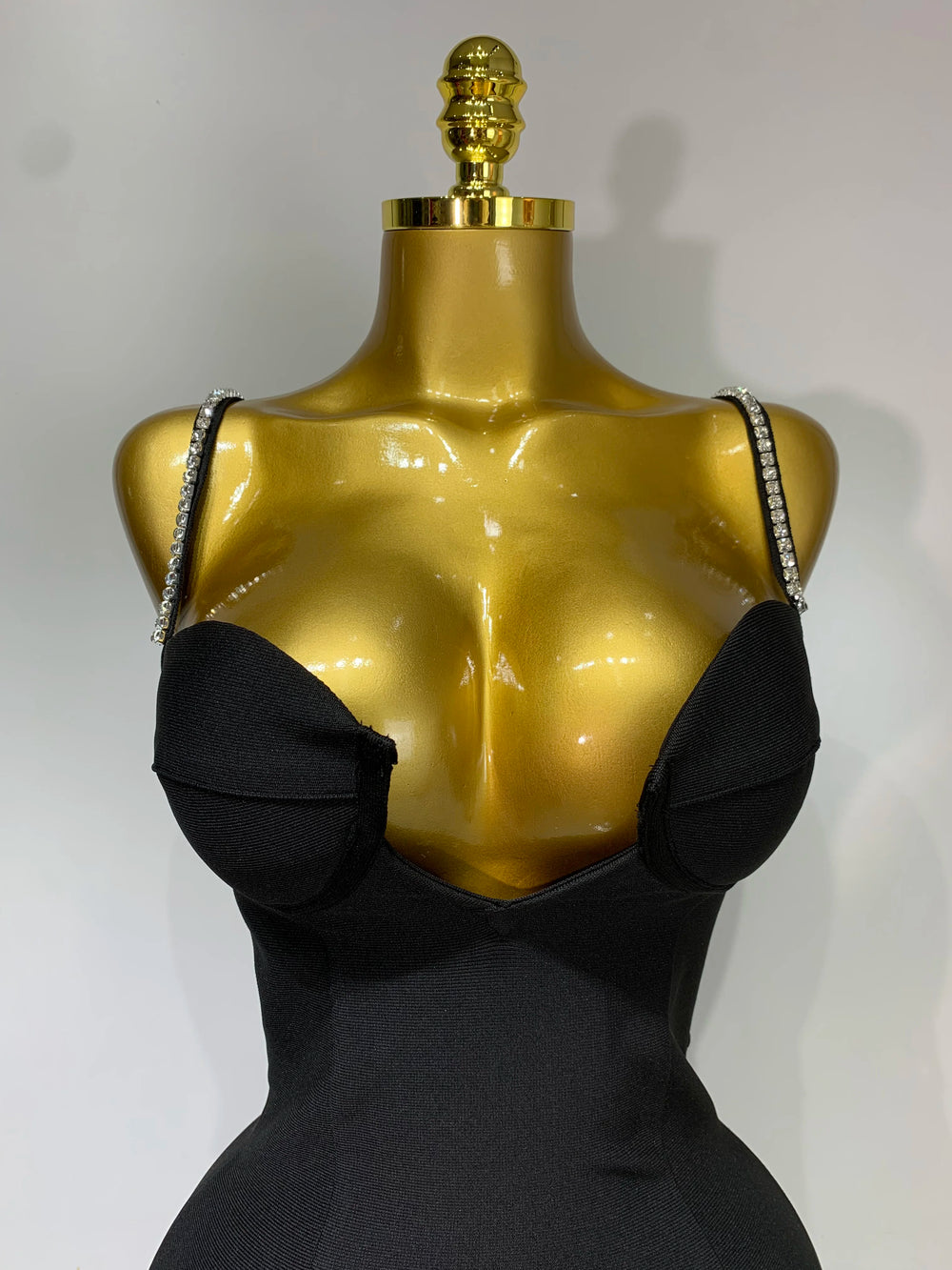 Black dress on a gold mannequin with a white background