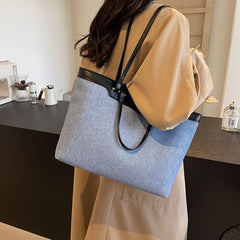 A woman carrying the denim tote bag over her shoulder, demonstrating its versatility and comfortable fit.